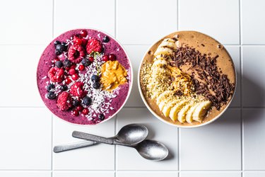 Chocolate and berry smoothie bowls on white background. Raw vegan food concept.