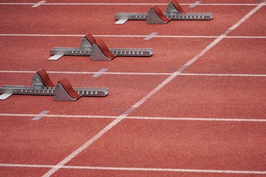 a close up of three sets of starting blocks placed on an athletics track for the start of a 100-meter sprint
